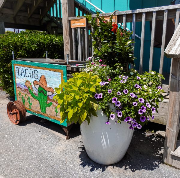 Large light-colored planter with flowers and foliage at a business entrance